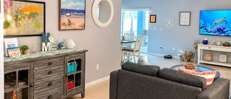 A living room with a gray sofa, a wooden cabinet with drawers, a globe, and a painting of a beach scene.