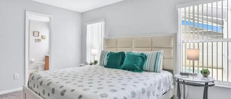 Une chambre à coucher avec un lit, un ventilateur de plafond, une fenêtre et une petite table avec une lampe.