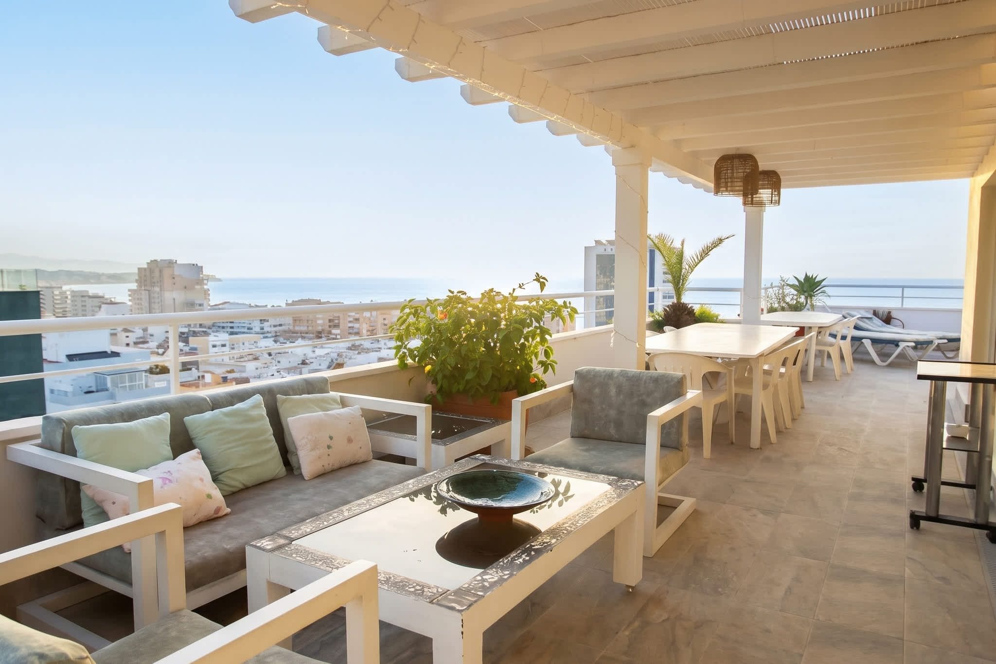 Une terrasse avec un espace salon, une table et une vue sur la mer.