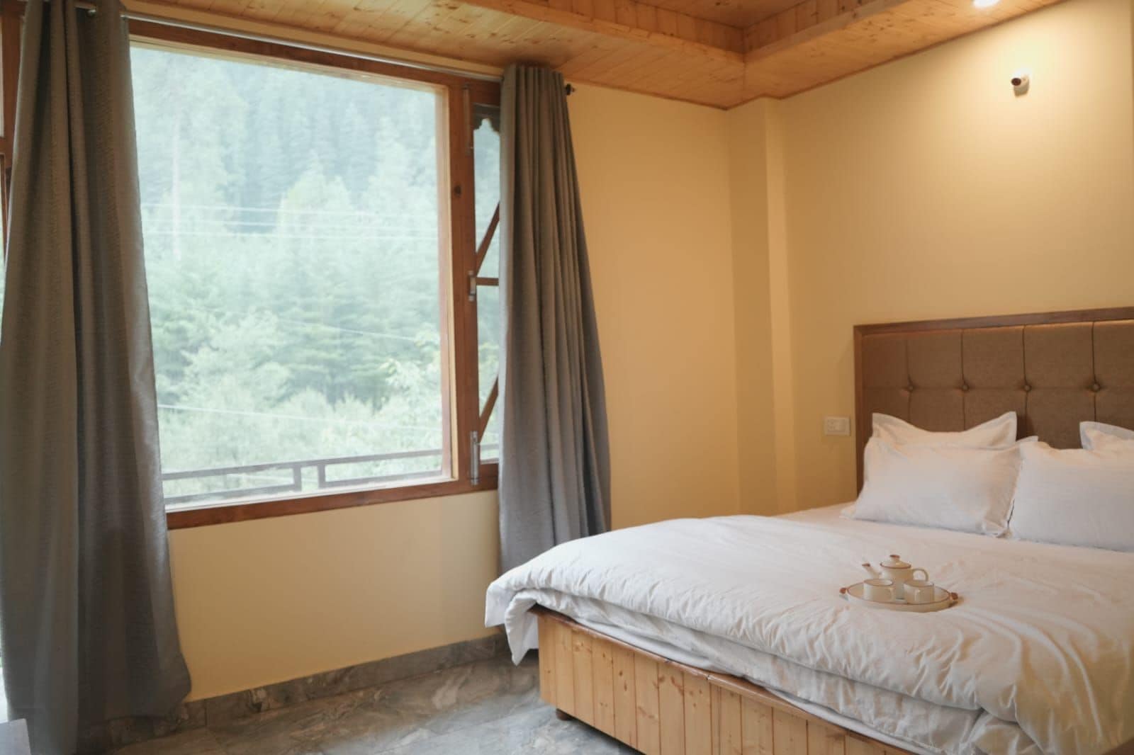 A bedroom with a bed, curtains, a window, and a headboard.