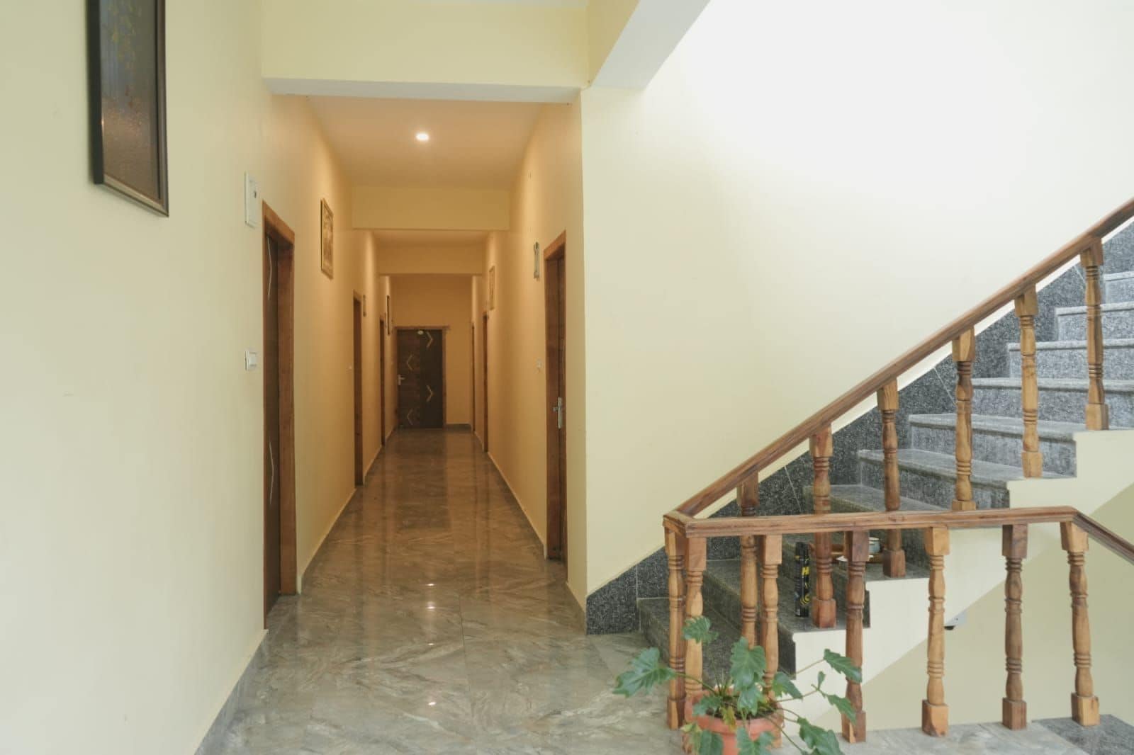 A hallway with a marble floor leading to a wooden staircase with a stone landing.