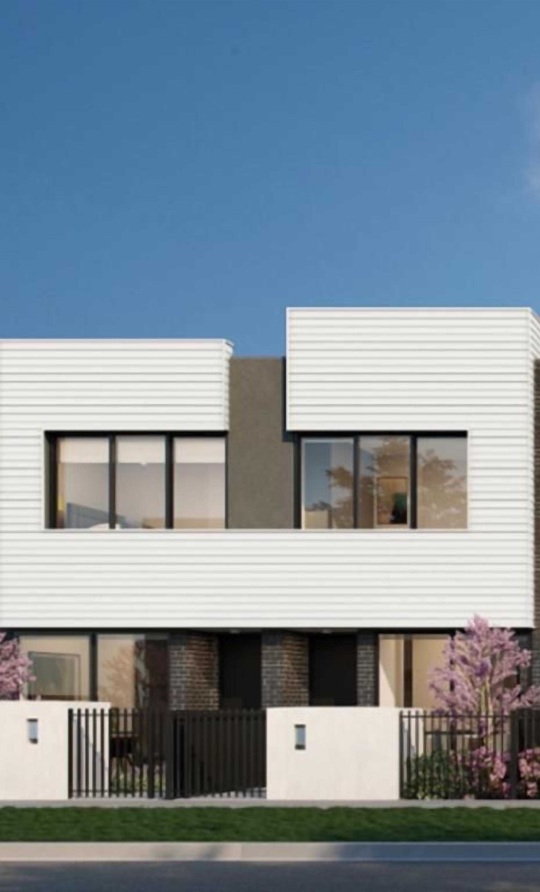 A modern two-story building with a flat roof, large windows, and a black fence in front.