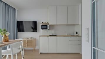 Una cocina moderna con armarios blancos, un microondas y un televisor de pantalla plana montado en la pared.