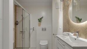 A modern bathroom with a glass shower enclosure, a white toilet, and a vanity with a mirror. - Gdynia Comfort Apartment Żeromskiego 7 (Gdynia)