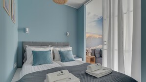 A bedroom with a bed, pillows, a nightstand, and a view of the outdoors. - Gdynia Comfort Apartment Żeromskiego 7 (Gdynia)