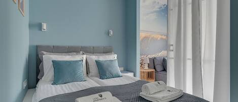 A bedroom with a bed, pillows, a nightstand, and a view of the outdoors.