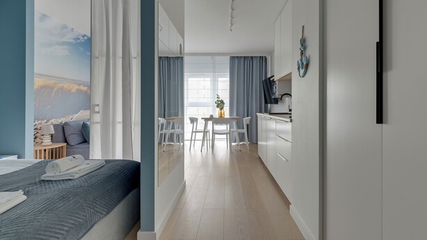 A modern hotel room with a bed, a desk, and a view of the sea. - Gdynia Comfort Apartment Żeromskiego 7 (Gdynia)