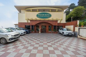 Un edificio con un letrero que dice 'Shilton Royal A Luxury Retreat' y un estacionamiento con varios autos.