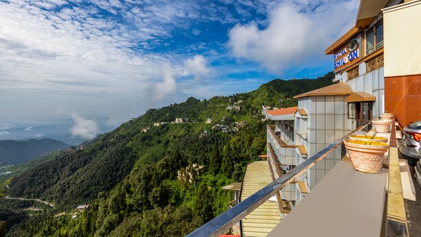 A hotel with a balcony overlooking a mountainous landscape.