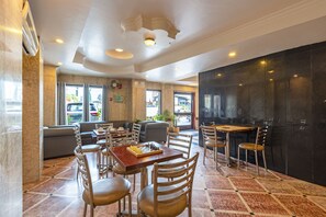 A restaurant with a chessboard on the table, multiple chairs, and a view of the street through large windows.