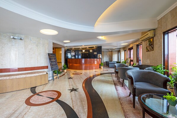 A hotel lobby with a reception desk, seating area, and a marble floor with star and circle patterns.