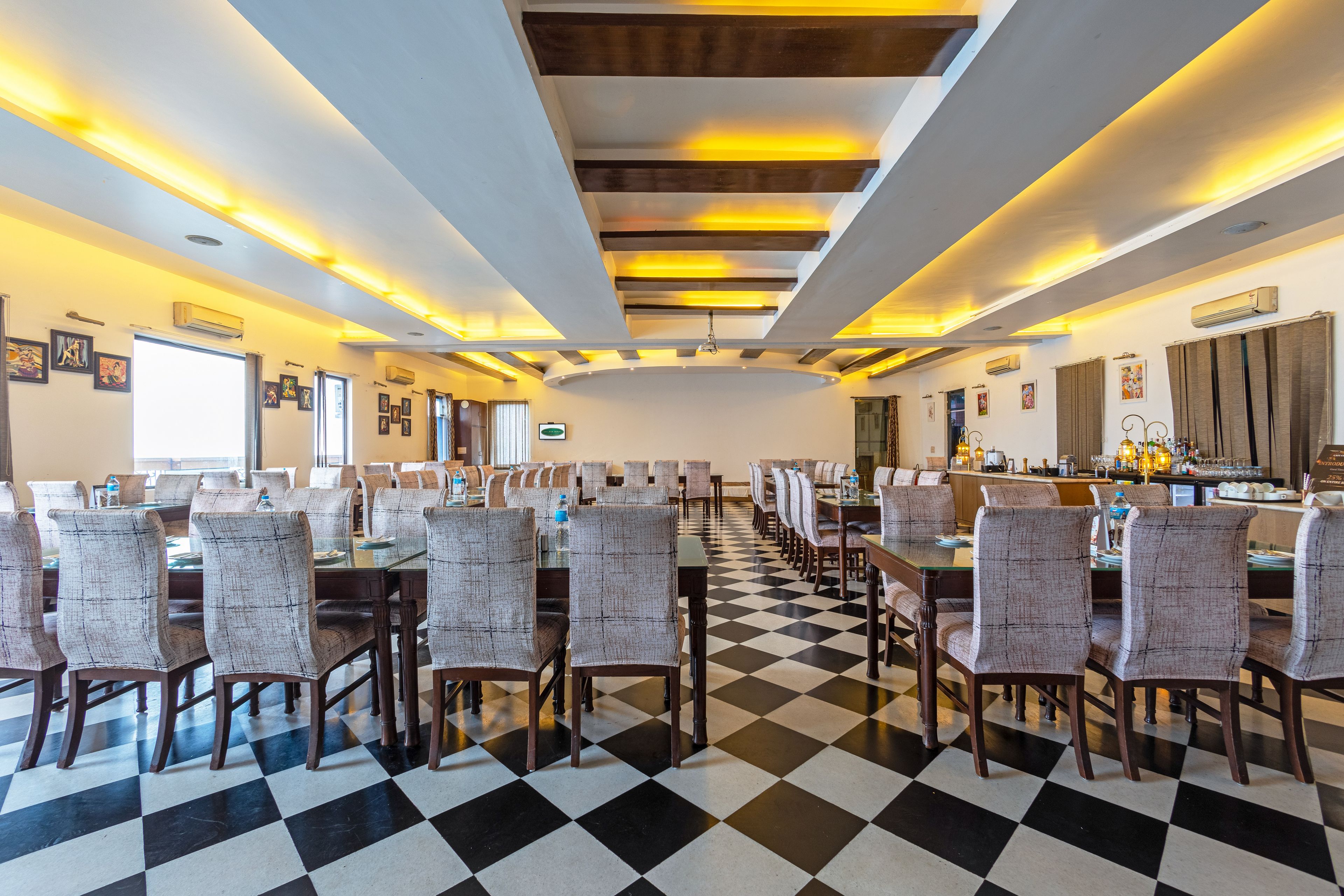 Uma sala de jantar de hotel com chão xadrez, várias mesas e cadeiras.