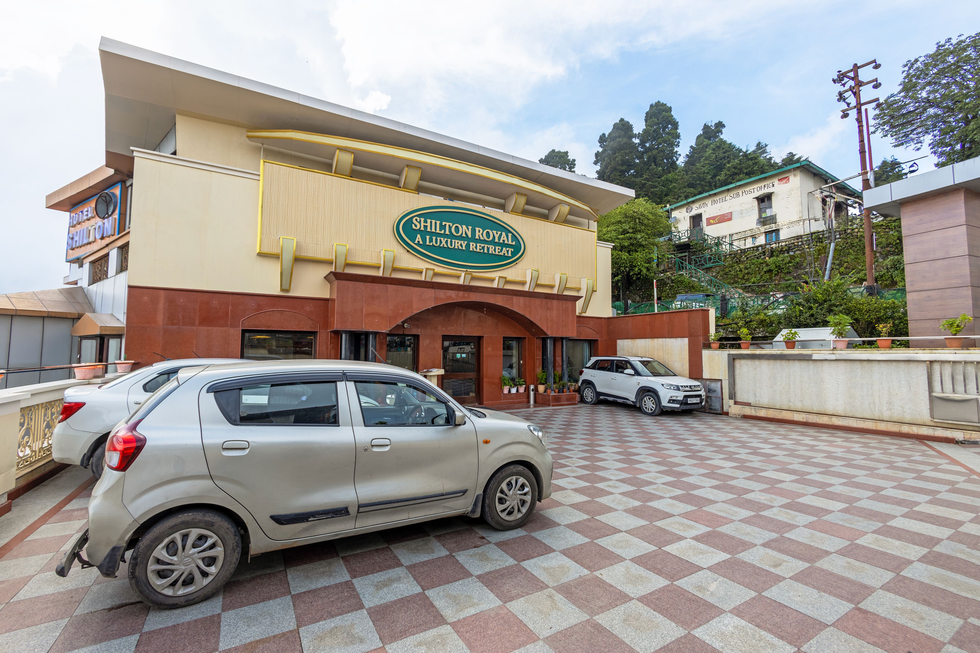 A hotel entrance with a checkered pavement and parked cars.