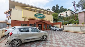 A hotel entrance with a checkered pavement and parked cars.