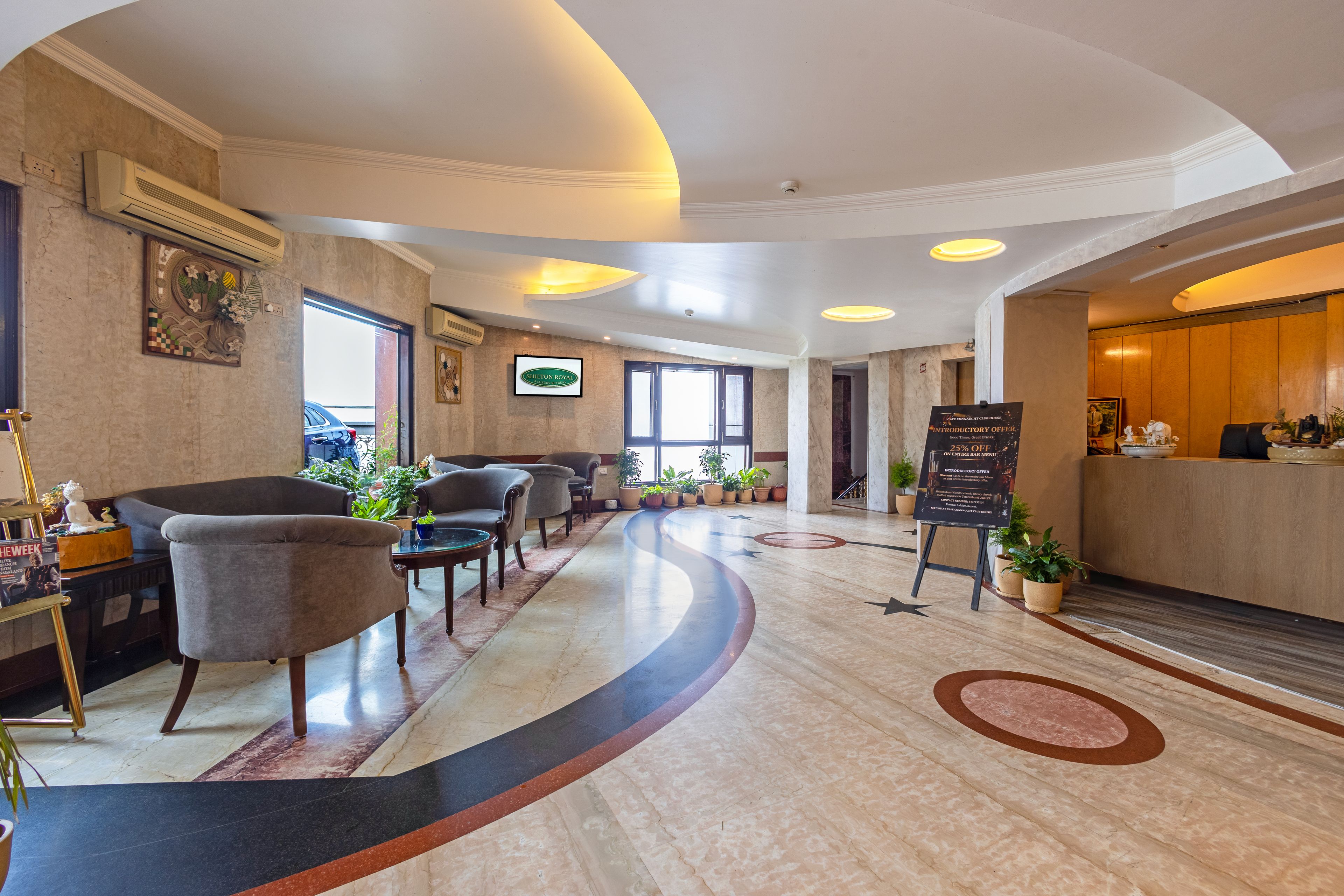 Un vestíbulo de hotel con una recepción, un área de estar y un amplio ventanal.