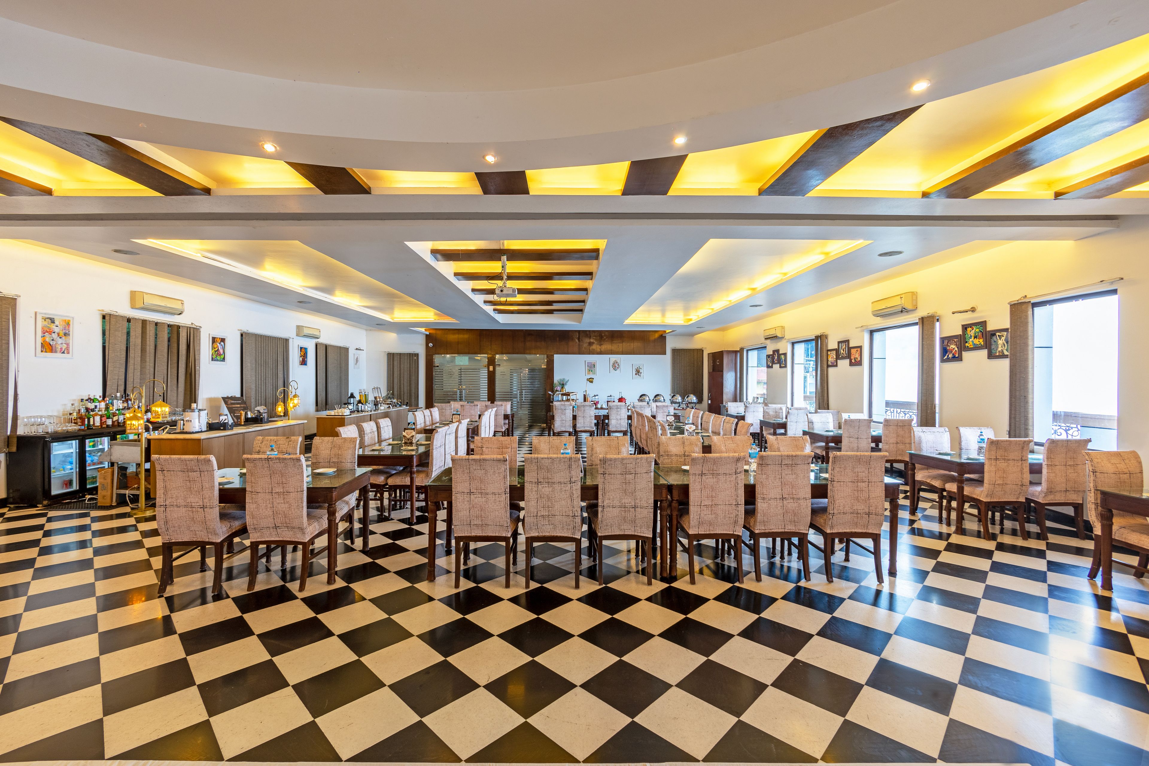 A spacious dining area with checkered flooring, multiple dining tables, and chairs.