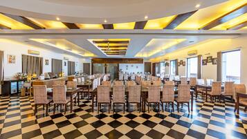 A spacious dining area with checkered flooring, multiple dining tables, and chairs.