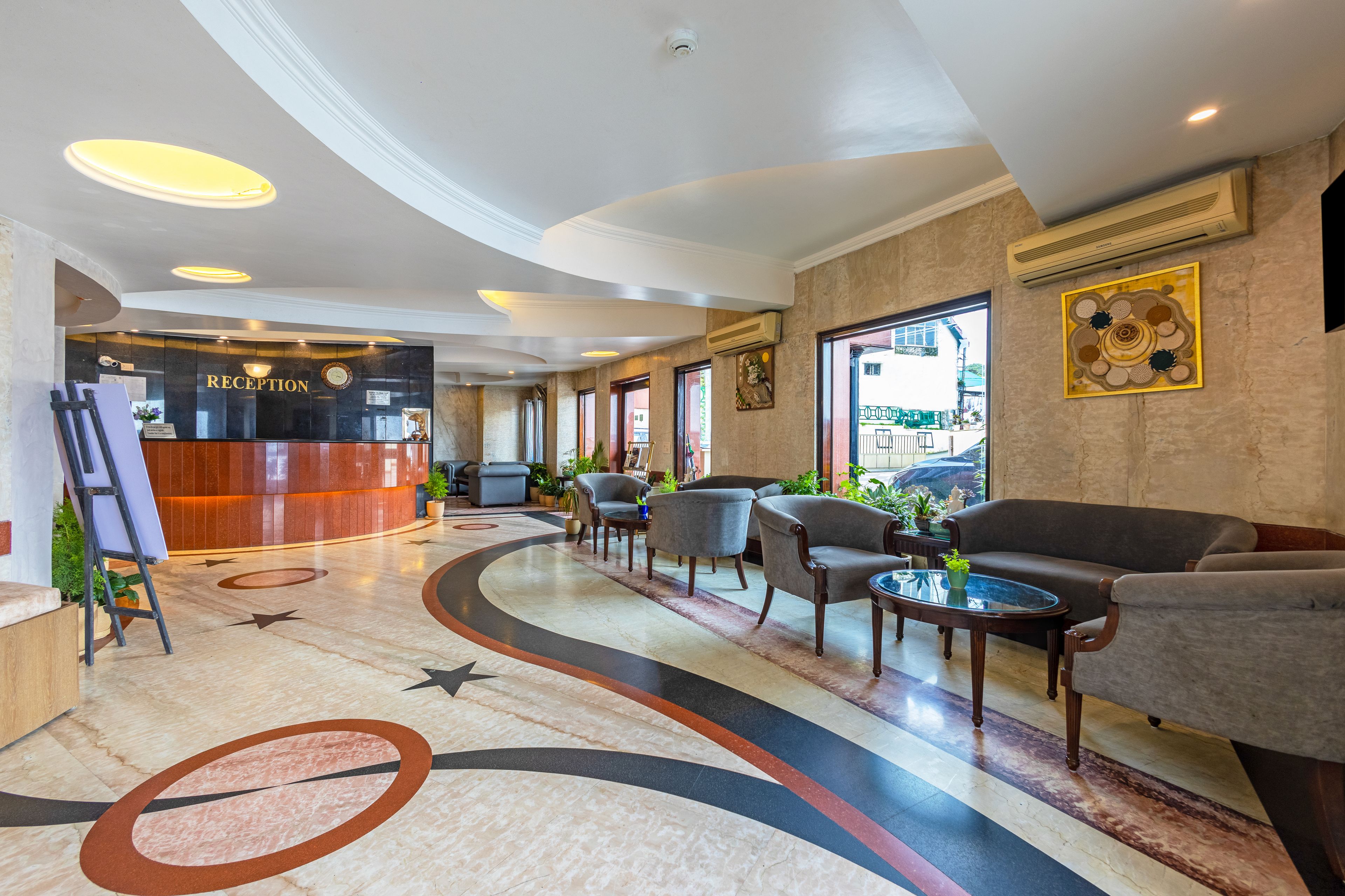 A reception area with a reception desk, seating area with sofas and armchairs, and a decorative floor design.