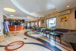 Un área de recepción con mostrador, zona de estar con sofás y sillones, y un diseño decorativo en el suelo.