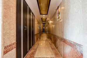 A corridor with marble flooring, dark wooden doors, and recessed lighting.