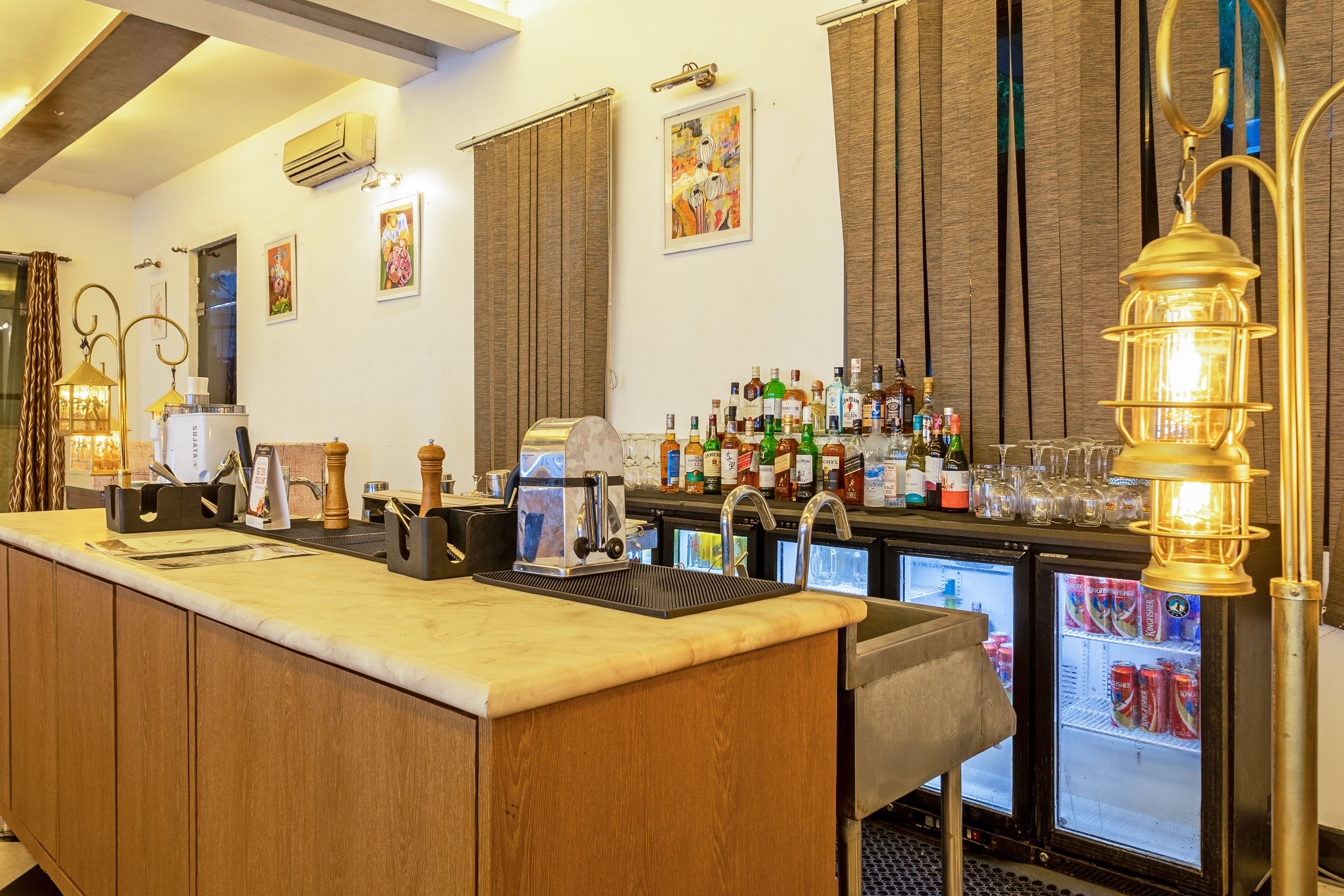 A bar area with a long counter, bar tools, and a variety of liquor bottles.