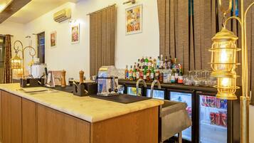 A bar area with a long counter, bar tools, and a variety of liquor bottles.