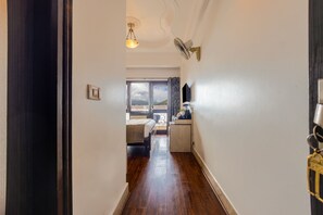 A hallway with a bed, a small kitchenette, and a view of the outdoors.