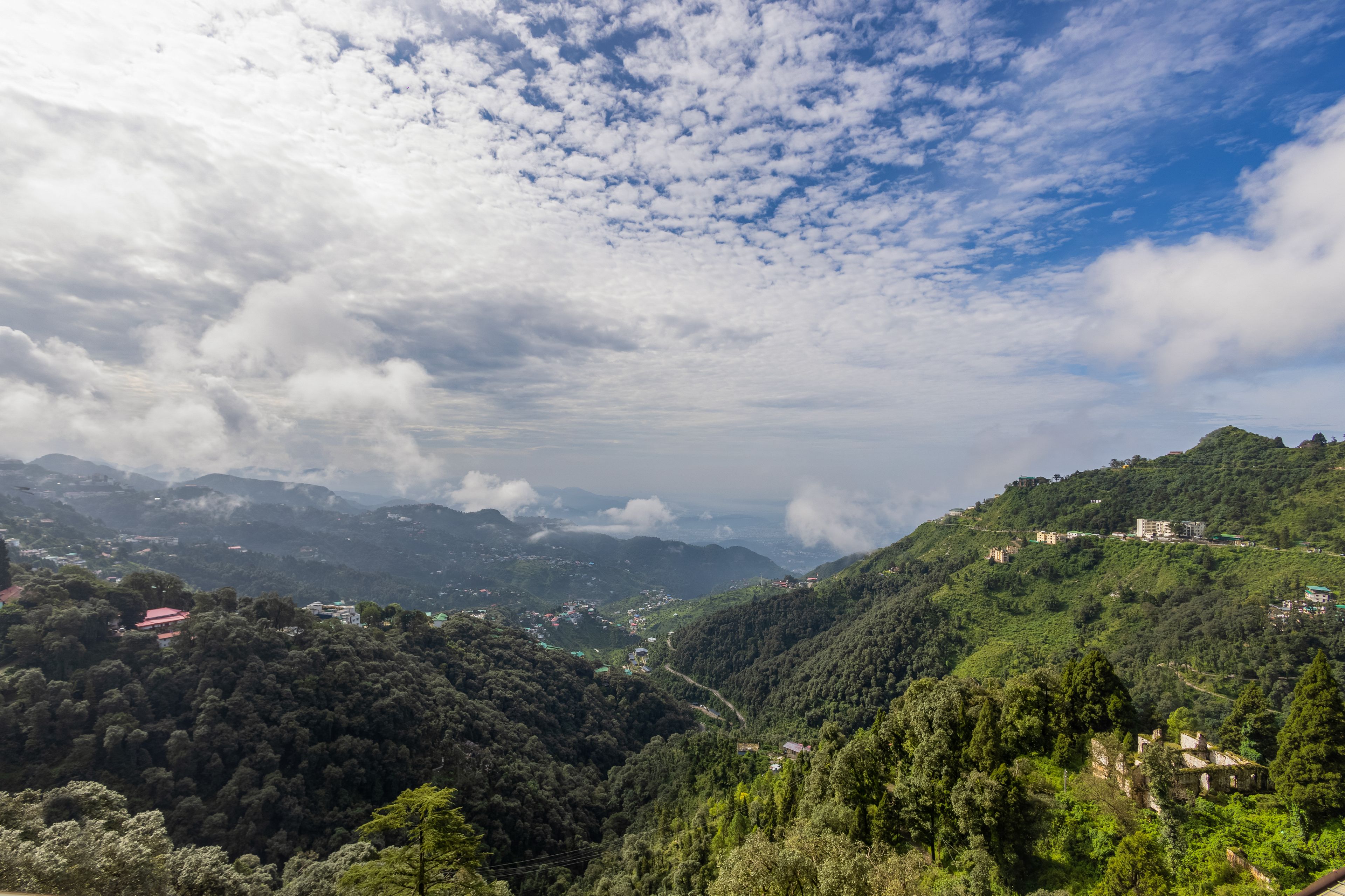Un paisaje montañoso con un valle y edificios dispersos.