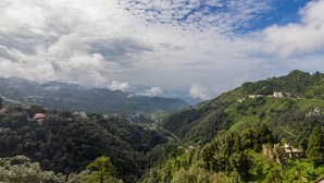 A mountainous landscape with a valley and scattered buildings.
