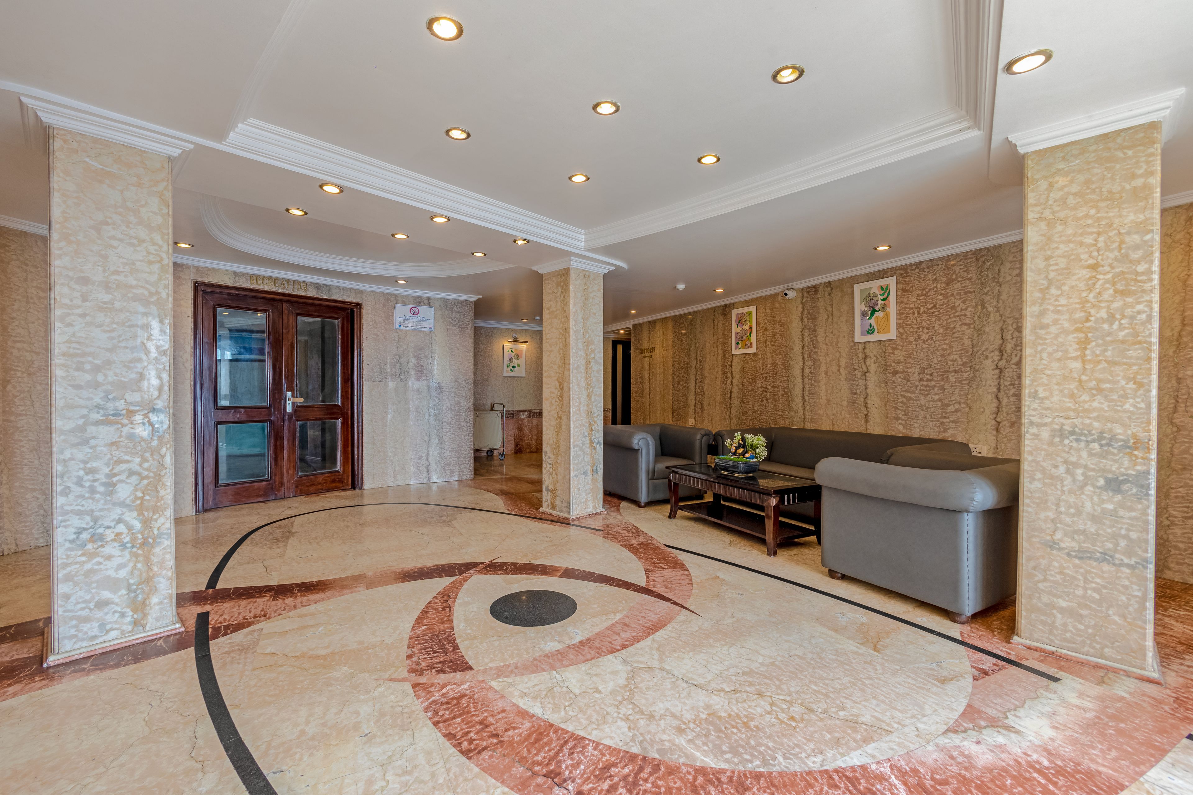 A lobby with a marble floor, a reception desk, a sofa, and a door labeled 'RECREATION'.