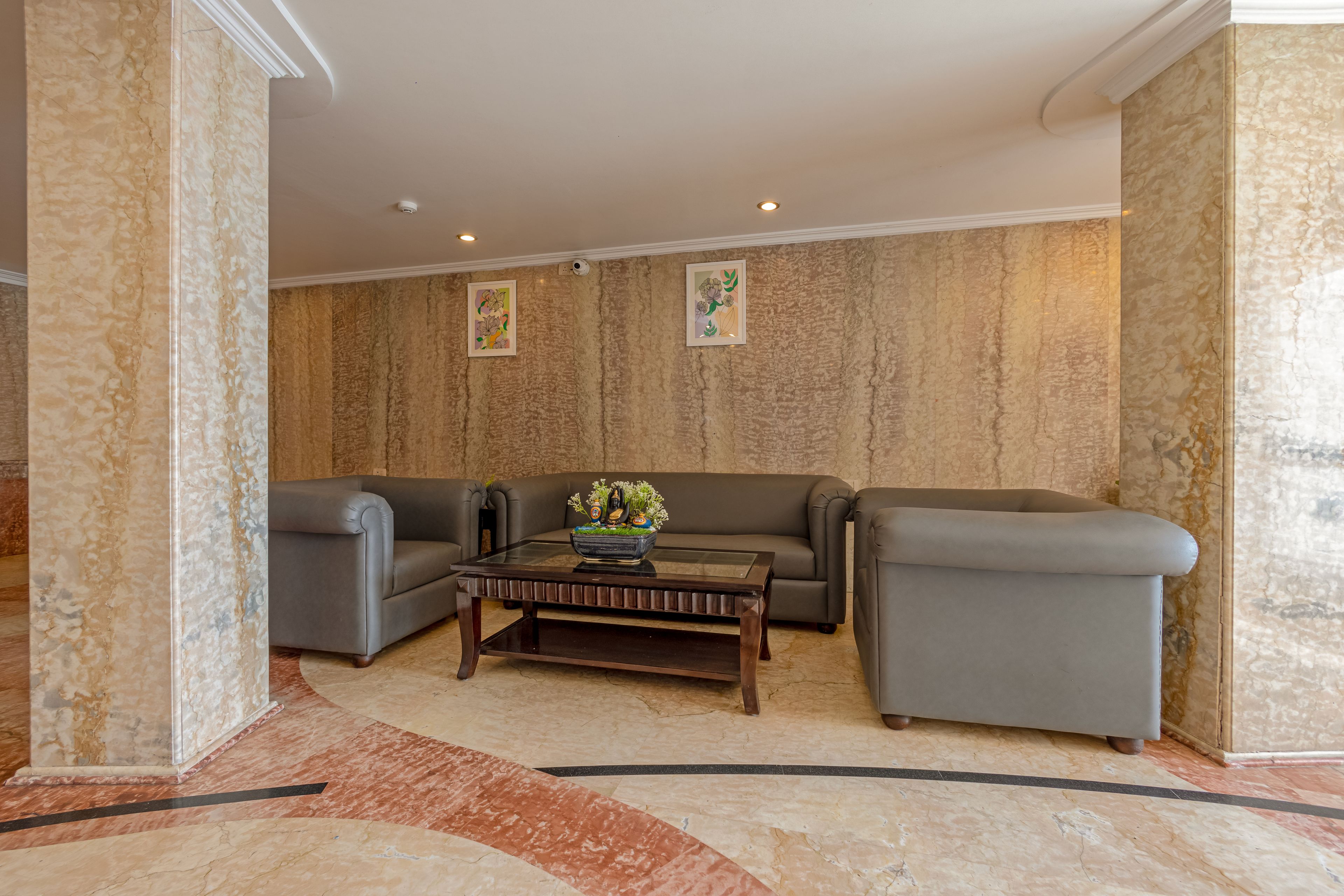 A modern lobby with a marble floor, a dark wooden coffee table, and two grey sofas.