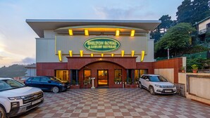 A hotel entrance with a checkered floor, a sign reading 'SHILTON ROYAL A LUXURY RETREAT', and cars parked in front.