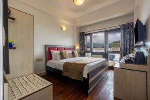 A hotel room with a bed, a desk, a chair, a window with a view, and a television.
