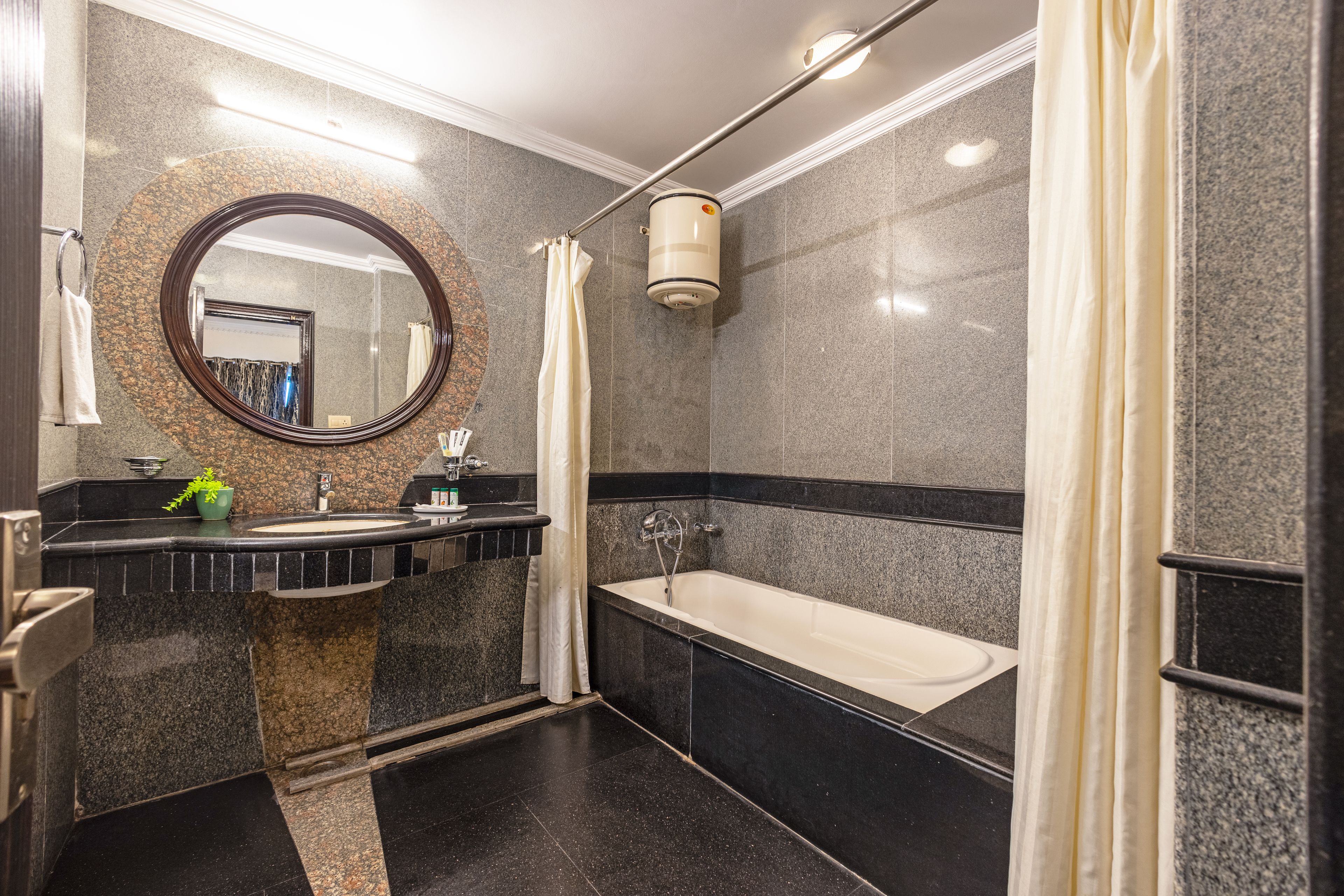 A modern bathroom with a freestanding bathtub, a large mirror, and a granite countertop.