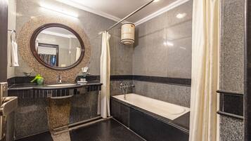 A modern bathroom with a freestanding bathtub, a large mirror, and a granite countertop.
