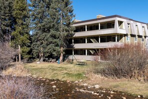 A multi-story building with a flat roof and a covered porch area. - Hi Country Haus Unit 1114 Downtown WP river view (Winter Park)