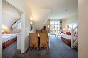 A hotel room with a dining area, a sofa, and a staircase. - Maisonette Ferienwohnung, Dierhagen (Ostseebad Dierhagen)