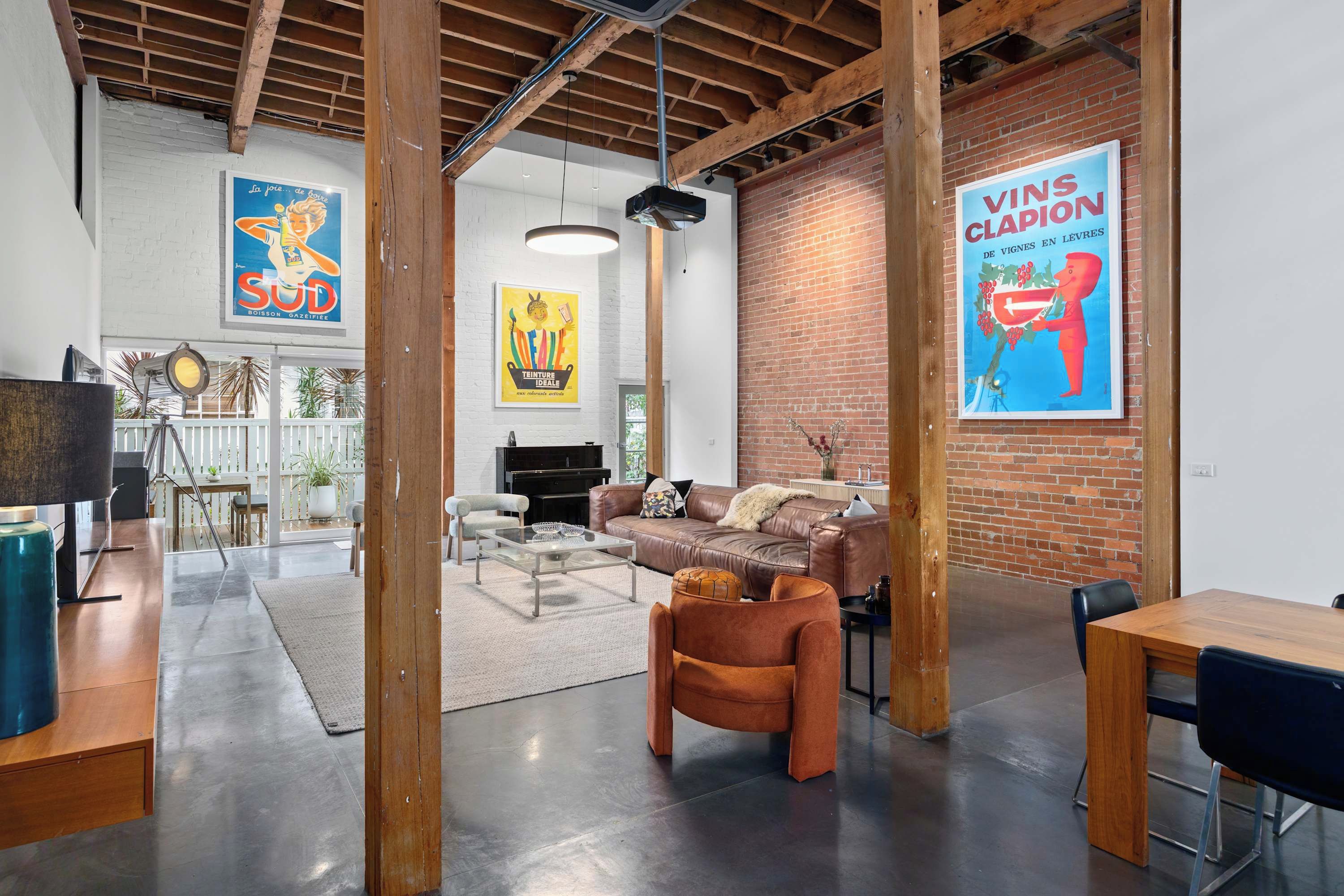 An open-plan living area with a brick wall, a sofa, a coffee table, and a television.