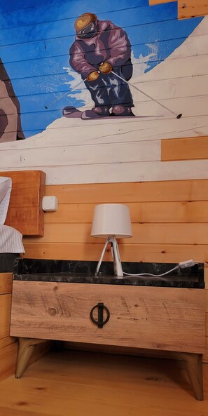 A wooden bed with a headboard, a bedside lamp, and a wall mural.