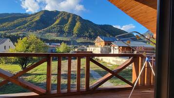 A wooden deck with a view of a mountain and a village.