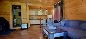 A wooden interior with a sofa, a table, and a kitchen area with cabinets and a sink.