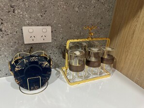 Ein dekoratives Objekt mit einer goldenen Hirschfigur obenauf, ein blaues Objekt mit Goldblattverzierungen und ein Glaswindlicht mit goldener Umrandung.