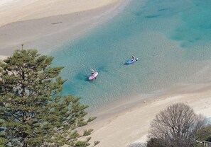 Una spiaggia con acqua cristallina, una persona su una tavola da paddleboard e una barca.