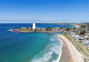 Un pueblo costero con playa, aguas azules cristalinas y una combinación de edificios residenciales y comerciales.