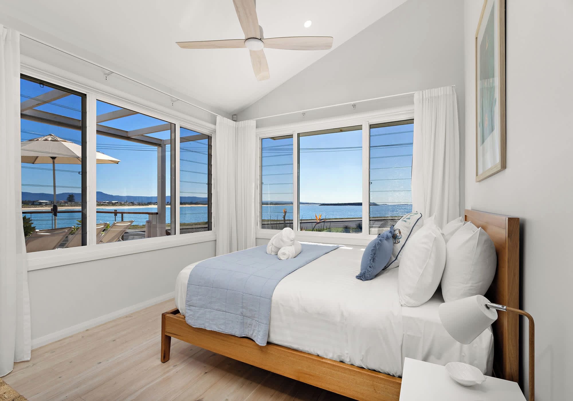 Ein Schlafzimmer mit einem großen Bett, einem Deckenventilator und Blick auf den Strand.