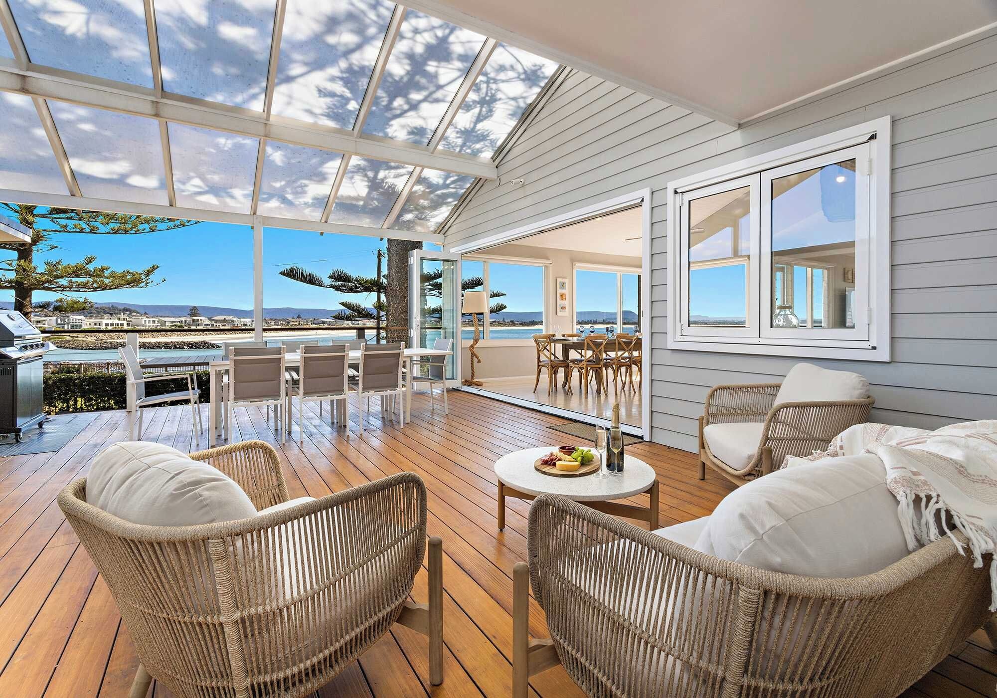 Un espace extérieur abrité, aménagé avec des meubles en osier, une table garnie de nourriture et de boissons, et offrant une vue sur la mer.