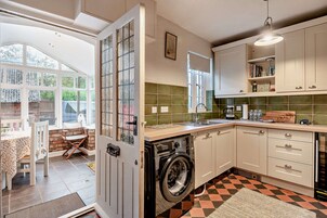 A kitchen with a washing machine, a sink, and a window.