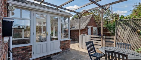 A conservatory with a brick wall, a white-framed glass door, and a stone floor.
