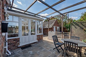 A conservatory with a brick wall, a white-framed glass door, and a stone floor.