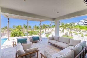 A modern outdoor lounge area with a pool, seating, and a view of a landscaped property. - Dolce Vita - Tropical Poolside Paradise (Sint Michiel)